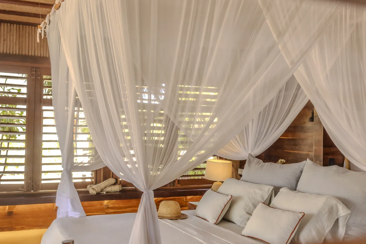 Dormitório com cortinado e vista para o jardim